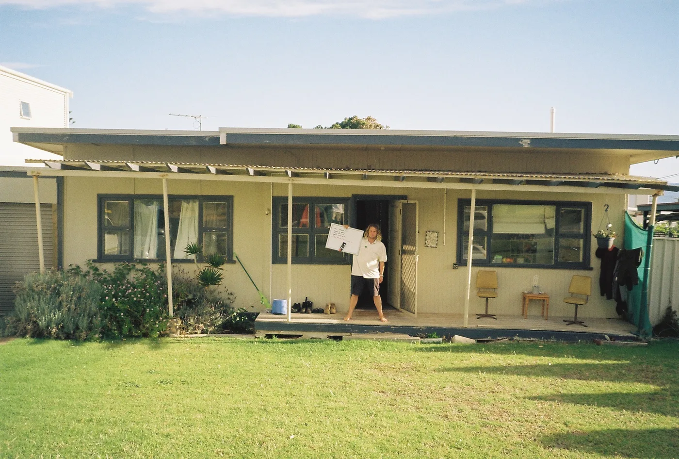 The Moana house from the back lawn, someone on the porch holding a whiteboard